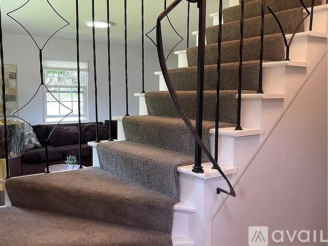 A staircase with a carpeted runner and black metal balusters.