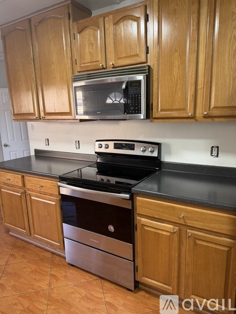 A kitchen with wooden cabinets and a black countertop.