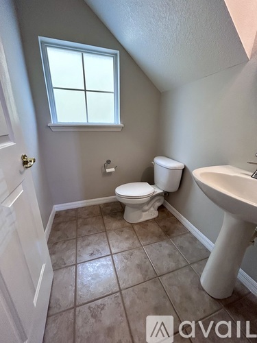 A bathroom with a toilet, sink, and window.
