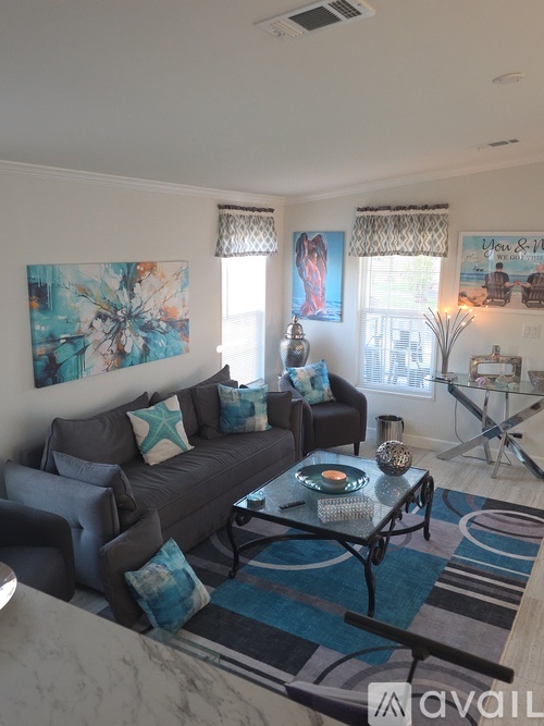 A living room with a grey couch, a coffee table, and a painting on the wall.