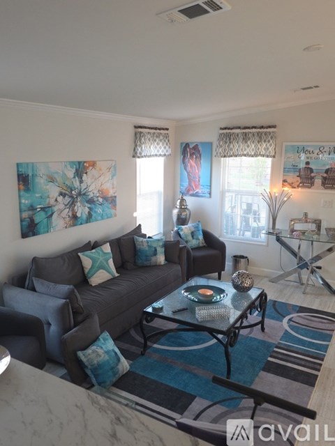 A living room with a grey couch, a coffee table, and a painting on the wall.