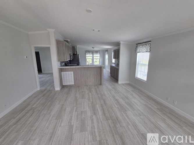 A spacious room with light wood flooring and white walls.