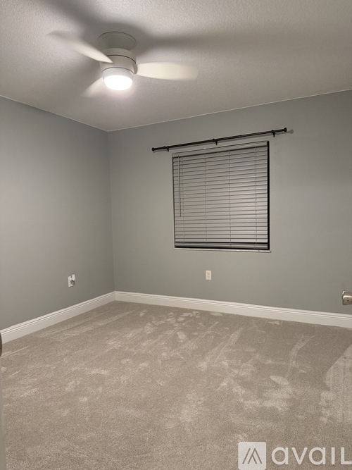 A room with a ceiling fan and a window with blinds.