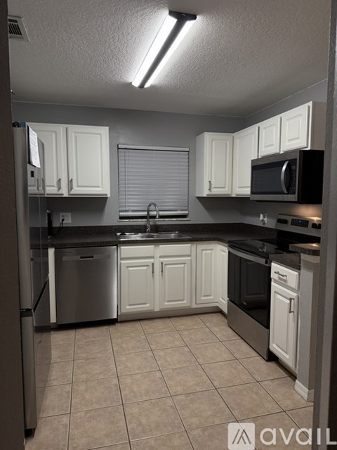 A kitchen with white cabinets and a black microwave.