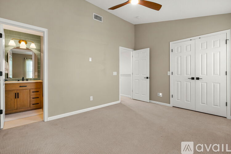 A spacious room with a ceiling fan and two doors.