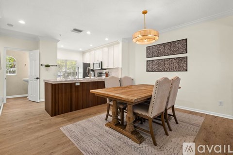 A kitchen with a wooden table and chairs in the foreground and a refrigerator in the background.