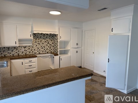 A kitchen with white cabinets and a brown countertop.
