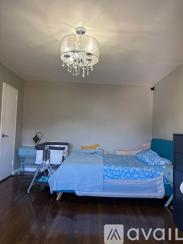 A bedroom with a bed, chair, and a chandelier.