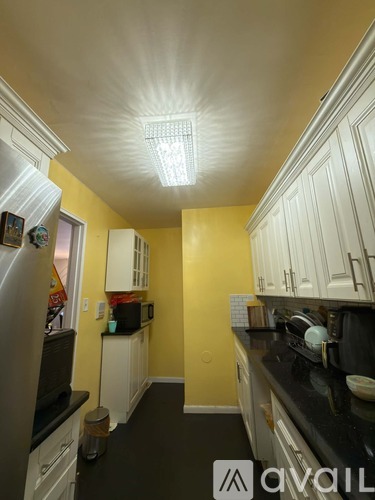 A kitchen with yellow walls and white cabinets.