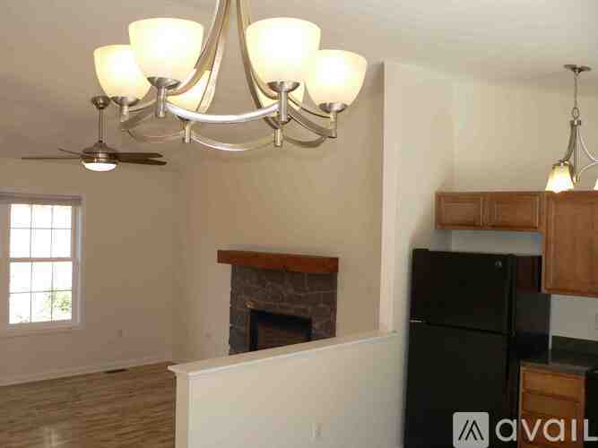 A living room with a fireplace and a black refrigerator.