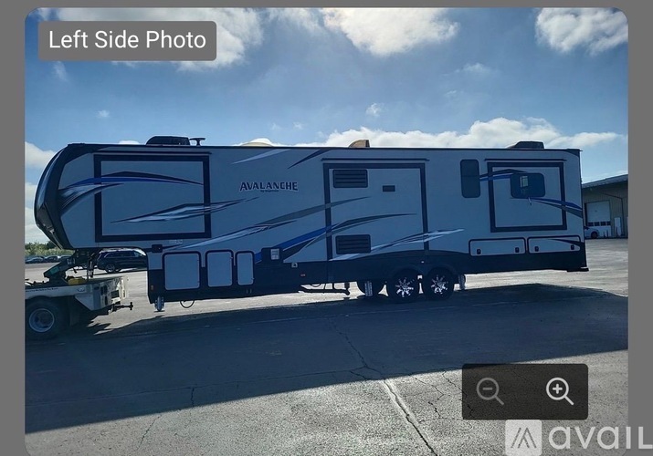 A large blue and white Avalanche RV is parked on a concrete surface.