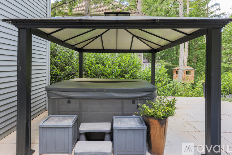 A hot tub is surrounded by a canopy and a few containers.