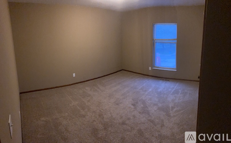 A room with a window and carpeted floor.