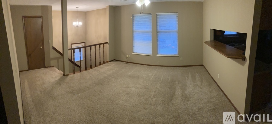 A living room with a carpeted floor and a window with blinds.