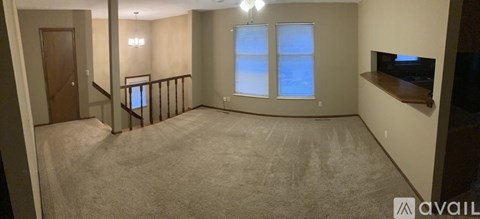 A living room with a carpeted floor and a window with blinds.