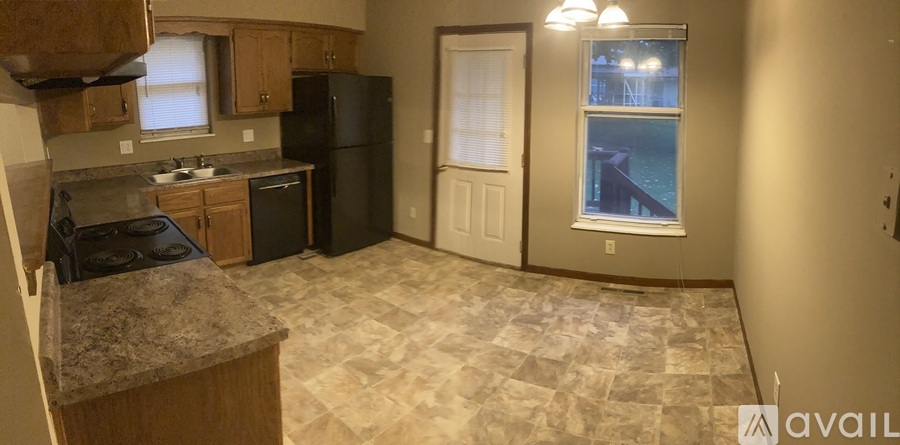 A kitchen with a black fridge and a window with a view of a pool outside.