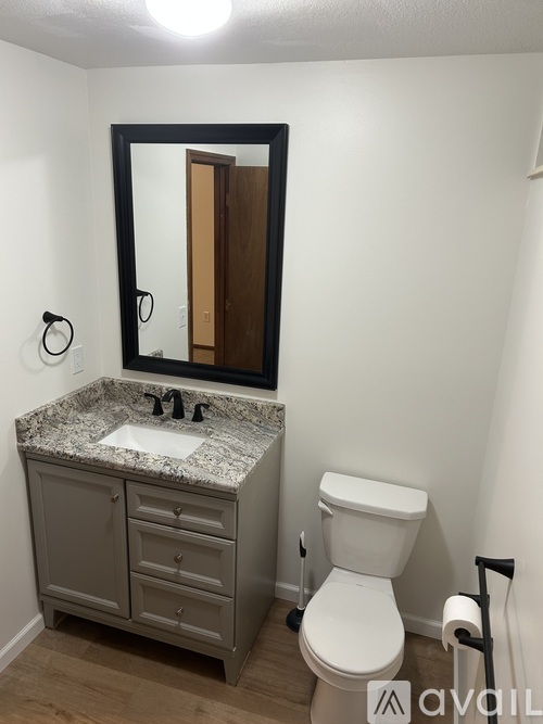 A bathroom with a toilet, sink and mirror.