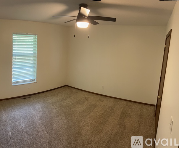 A room with a ceiling fan and a window with blinds.