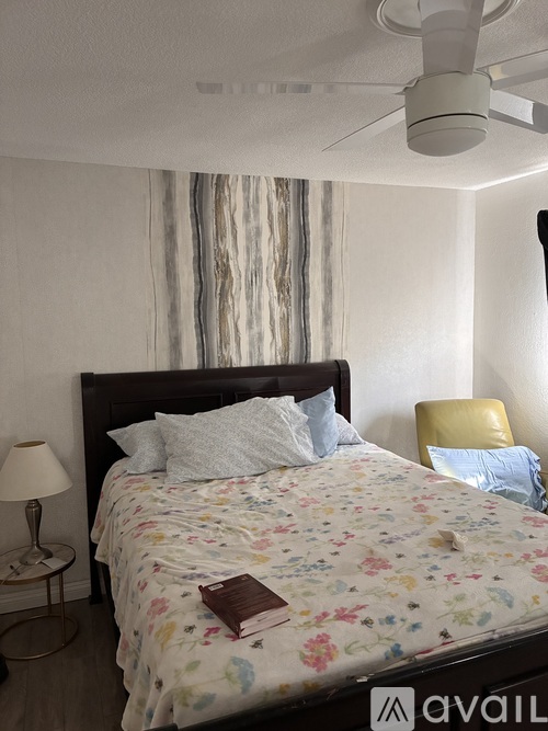 A bedroom with a floral bedspread and a ceiling fan.