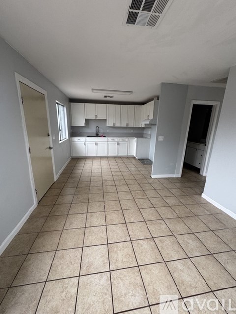 A kitchen with white cabinets and a tiled floor.