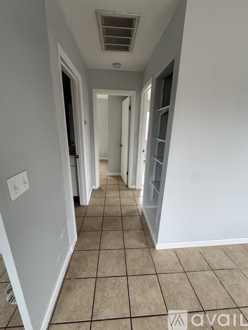 A long hallway with white walls and tiled flooring.