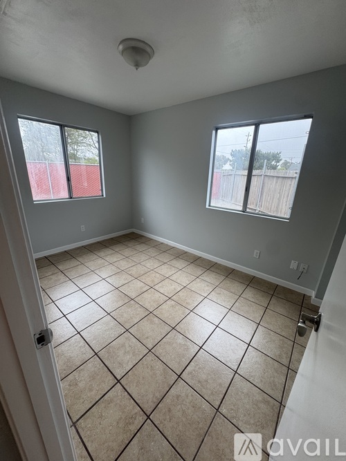 A room with tiled flooring and two windows.
