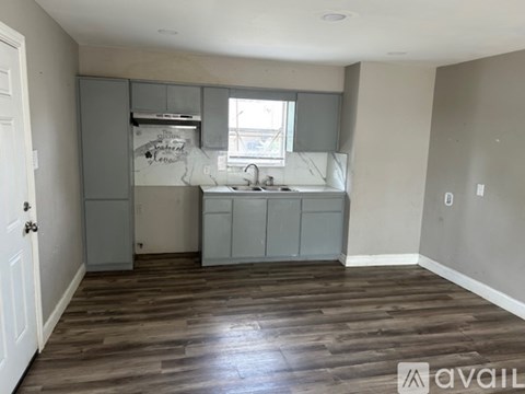 A kitchen with wooden floors and grey cabinets is available.
