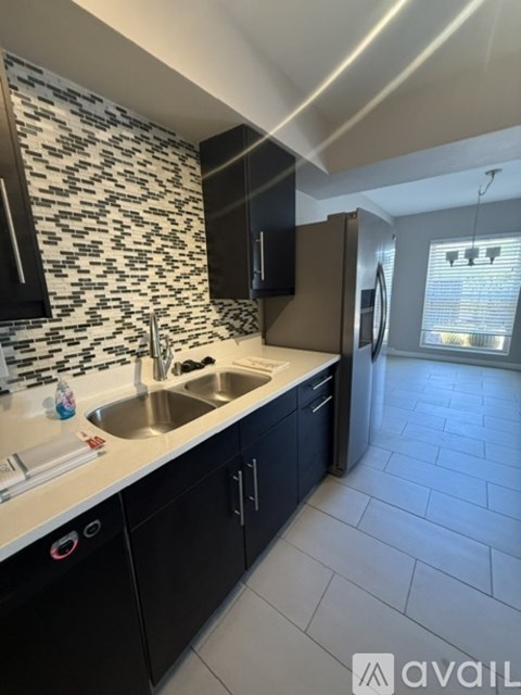 A kitchen with black cabinets and a patterned backsplash.