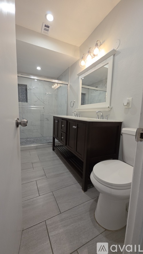 A bathroom with a toilet, sink, and mirror.