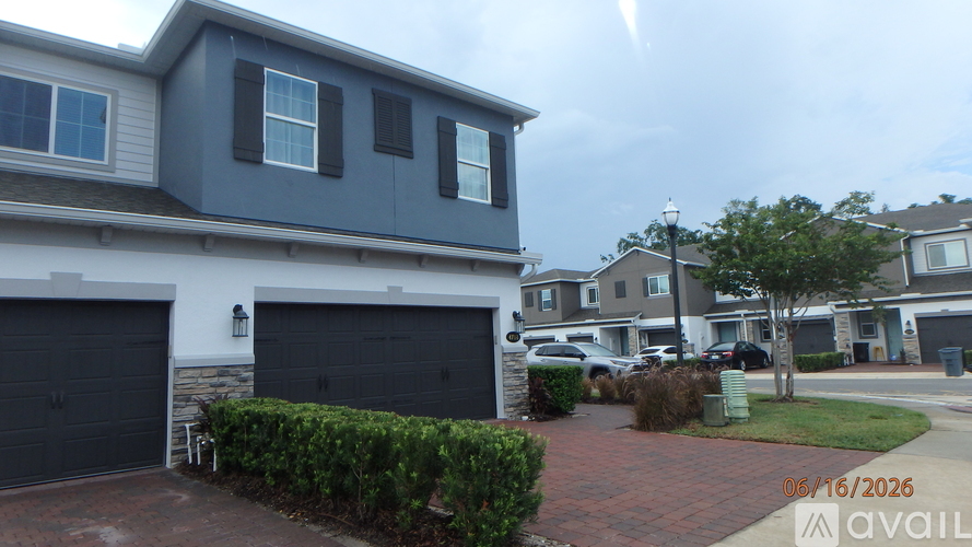 A house with a garage and a hedge in front of it.