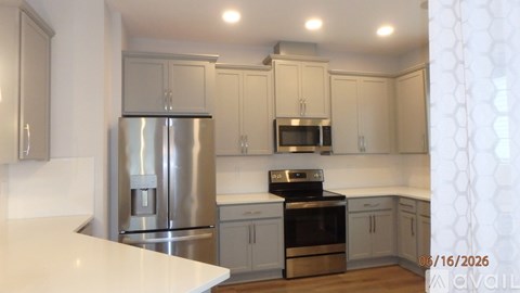 A kitchen with a stainless steel refrigerator and a black stove top oven.