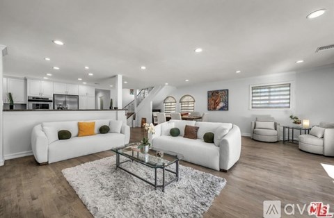 A modern living room with white furniture and a glass coffee table.