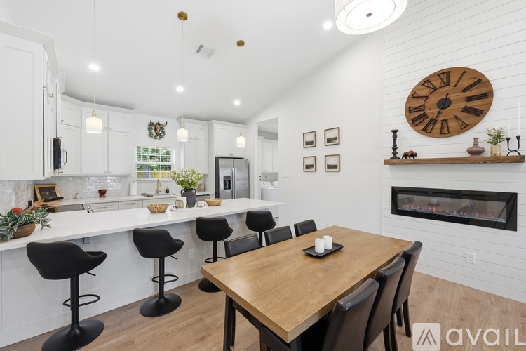 A modern kitchen with a wooden table and black bar stools.