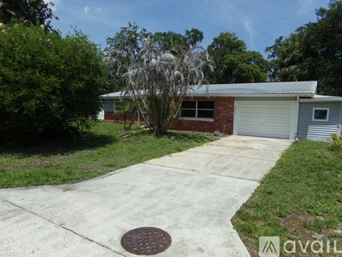 A house with a driveway and a tree in front.