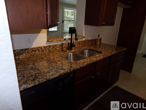 A kitchen with granite countertops and dark brown cabinets.