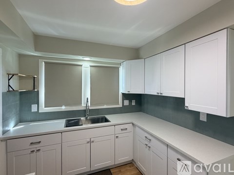 A kitchen with white cabinets and a grey backsplash.