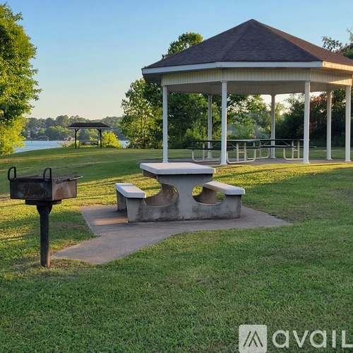 A gazebo with a picnic table in front of a lake.