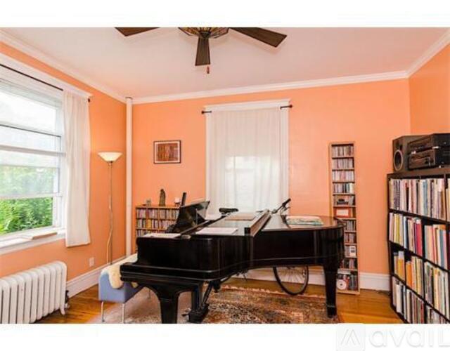A black grand piano sits in a room with orange walls.