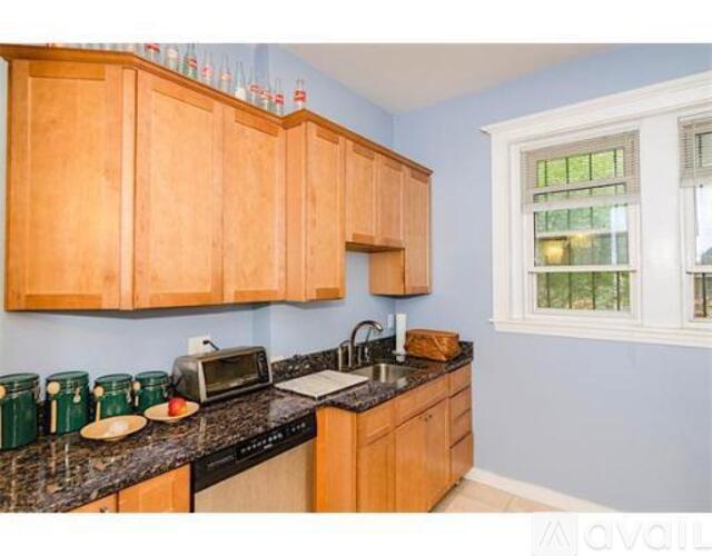 A kitchen with wooden cabinets and a black countertop.
