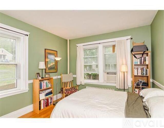A bedroom with a bed, a chair, a window, and a bookshelf.