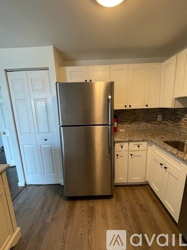A kitchen with a stainless steel refrigerator and white cabinets.