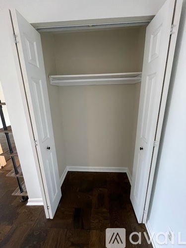 A white closet with a shelf and a wooden floor.