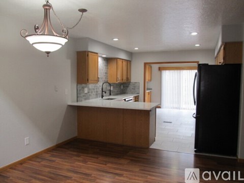 A kitchen with wooden cabinets and a black refrigerator.