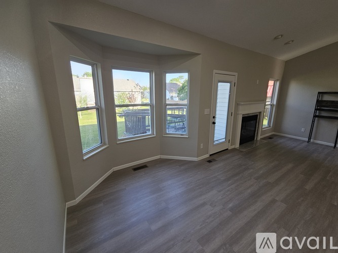 A spacious room with large windows and wooden flooring.