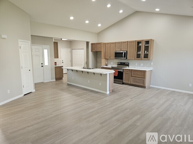 A spacious kitchen with wooden flooring and modern appliances.
