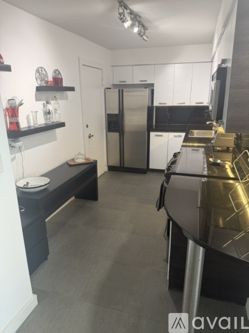 A kitchen with a black countertop and a stainless steel refrigerator.