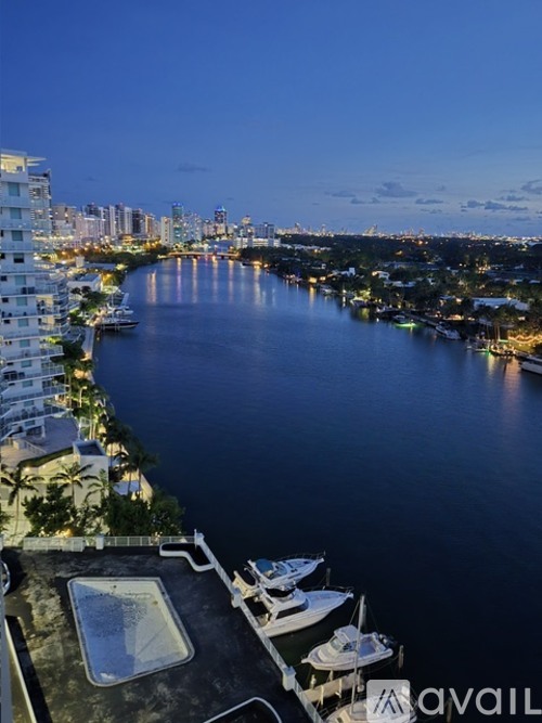 A marina at dusk with boats docked and buildings along the water.