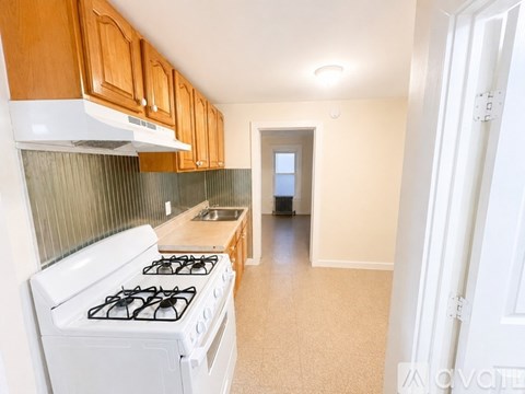 A kitchen with a white gas stove and wooden cabinets.
