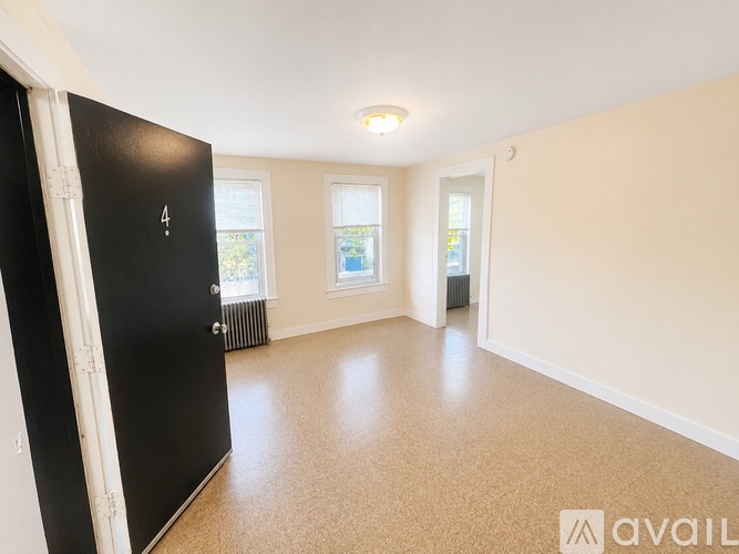 A room with a black door and a window with a view of trees.