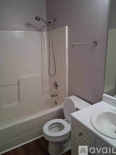 A white toilet is in a bathroom with a white tub and sink.